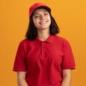happy young delivery girl red uniform cap smiling cheerfully standing orange wall